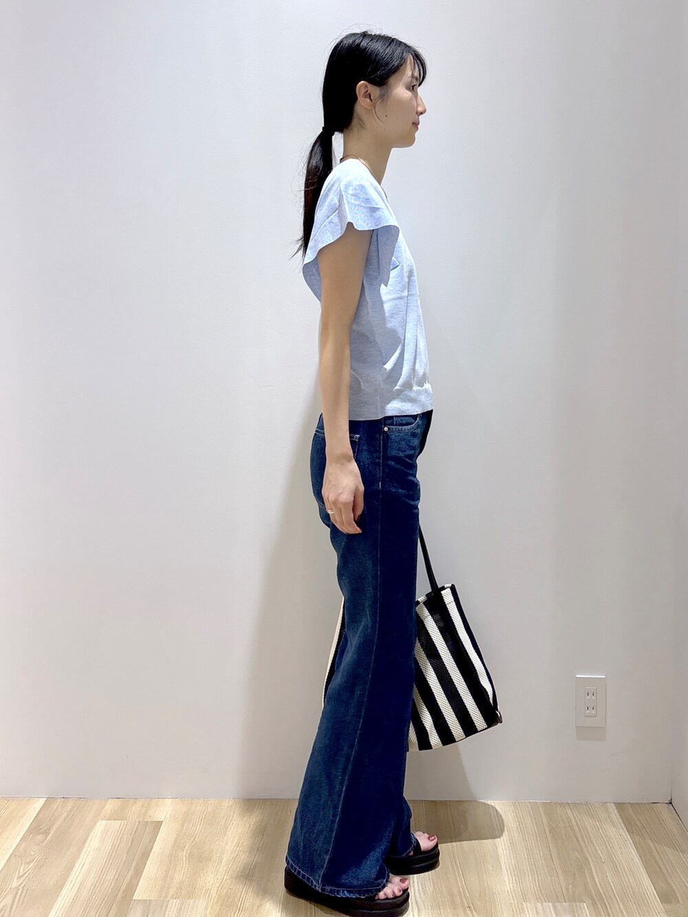 ブルー系のニット/セーター、ブルー系のデニムパンツ、ブラック系のトートバッグを着用したレディースの夏コーディネートの5枚目の写真