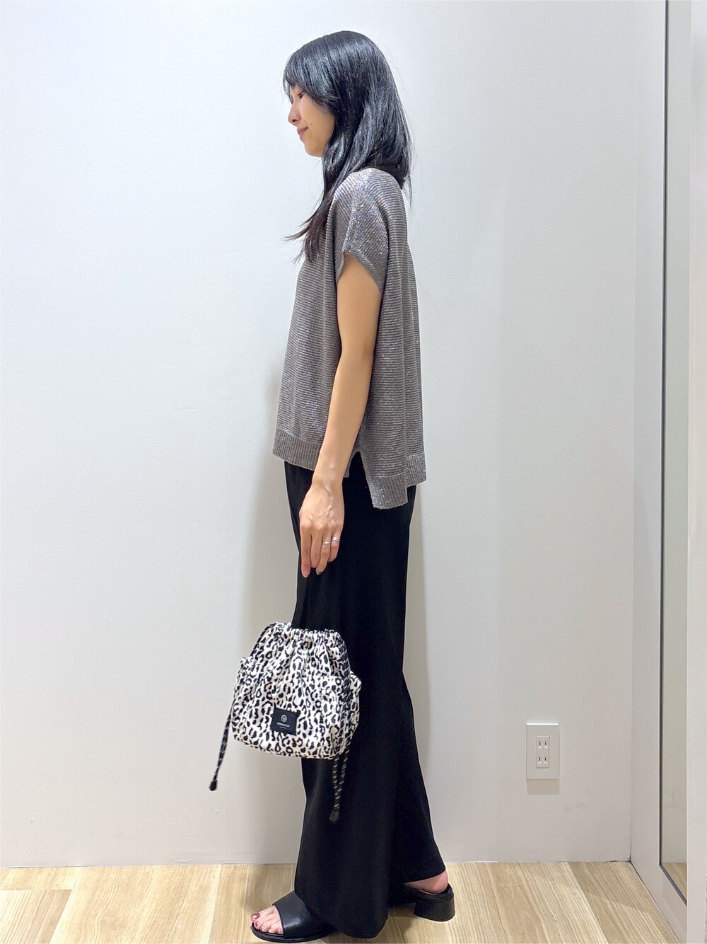 グレー系のニット/セーター、ブラック系のその他パンツ、ベージュ系のショルダーバッグを着用したレディースの夏コーディネートの3枚目の写真