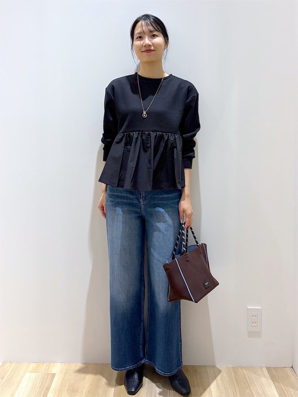 ブラック系のTシャツ/カットソー、ブルー系のデニムパンツ、ブラウン系のトートバッグを着用したレディースの秋コーディネートの8枚目の写真