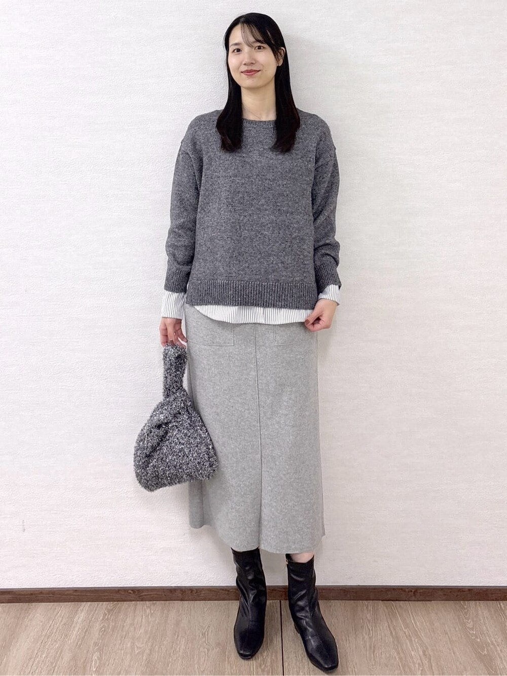 ブラック系のノーカラーコート、グレー系のニット/セーター、ホワイト系のTシャツ/カットソーを着用したレディースの冬コーディネートの8枚目の写真