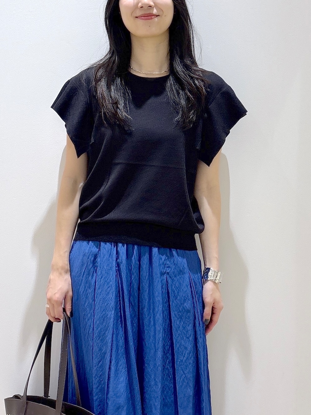 ブラック系のニット/セーター、ブルー系のその他パンツ、ブラウン系のトートバッグを着用したレディースの夏コーディネートの6枚目の写真