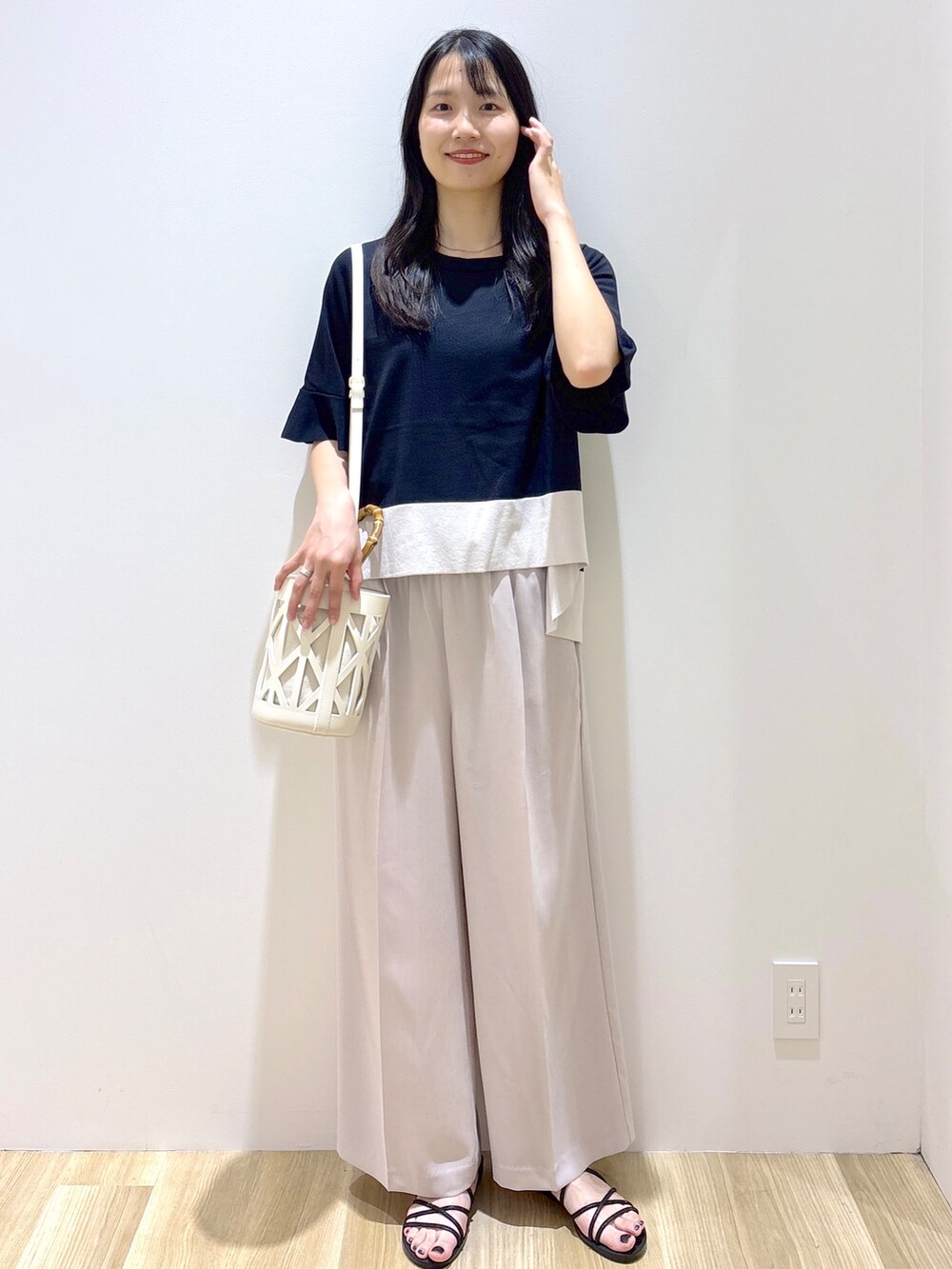 ブラック系のニット/セーター、ベージュ系のその他パンツ、ホワイト系のハンドバッグを着用したレディースの夏コーディネートの2枚目の写真