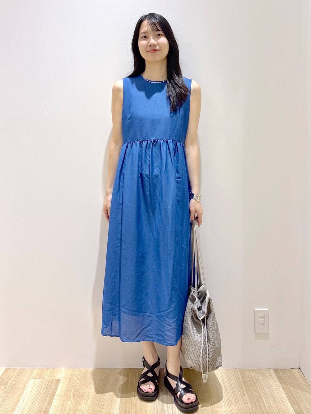 ブルー系のワンピース、ホワイト系のトートバッグ、ブラック系のサンダルを着用したレディースの夏コーディネートの2枚目の写真
