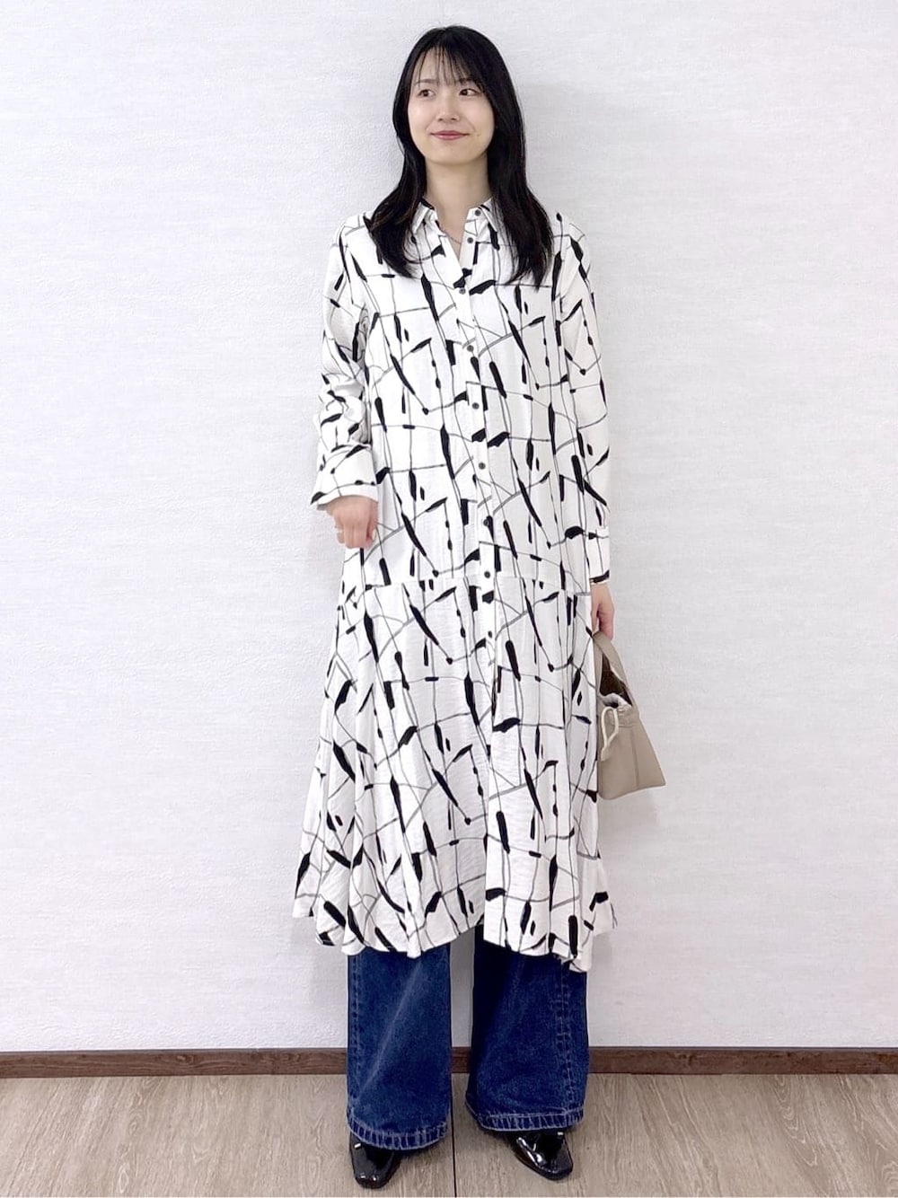 ベージュ系のワンピース、ブルー系のデニムパンツ、ベージュ系のショルダーバッグを着用したレディースの春コーディネートの2枚目の写真