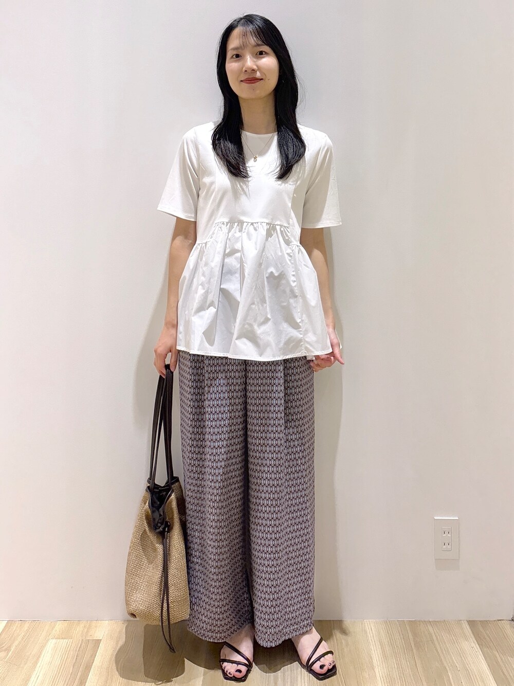 ブラウン系のサンダル、ベージュ系のトートバッグ、ホワイト系のTシャツ/カットソーを着用したレディースの春コーディネートの6枚目の写真
