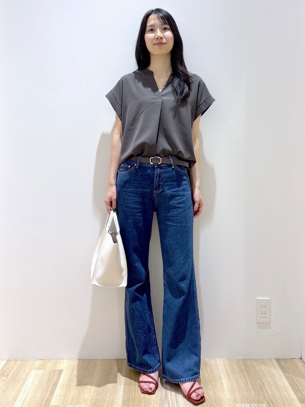 ブルー系のデニムパンツ、ホワイト系のショルダーバッグ、レッド系のサンダルを着用したレディースの夏コーディネートの2枚目の写真