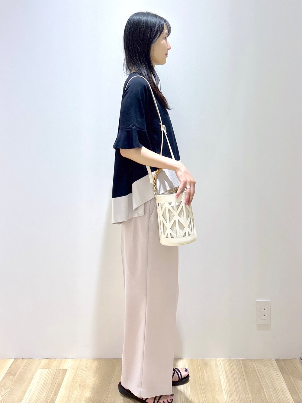 ブラック系のニット/セーター、ベージュ系のその他パンツ、ホワイト系のハンドバッグを着用したレディースの夏コーディネートの5枚目の写真