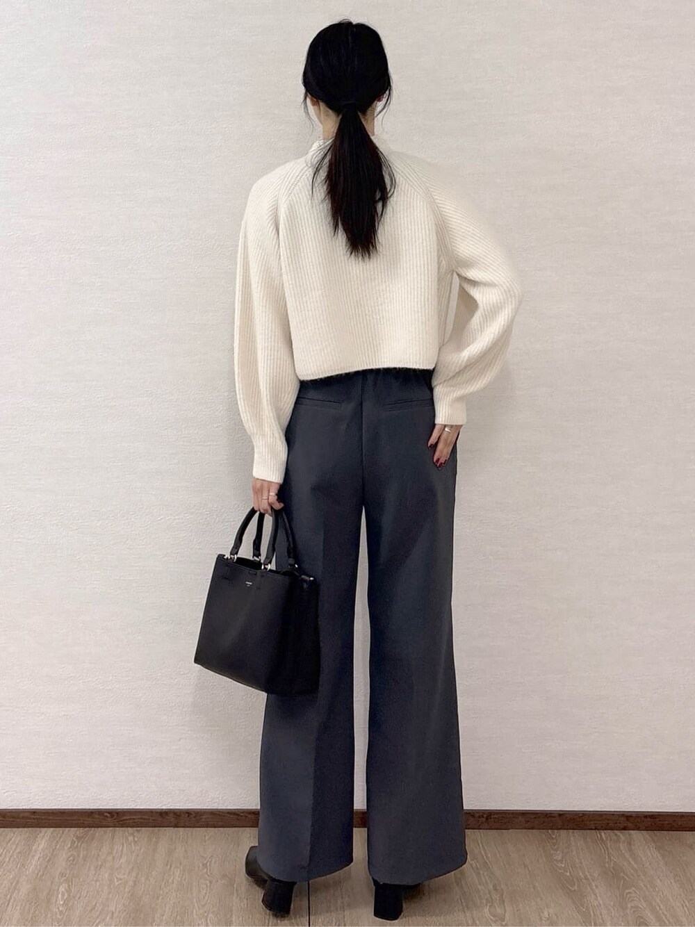 ホワイト系のニット/セーター、グレー系のその他パンツ、ブラック系のトートバッグを着用したレディースの冬コーディネートの4枚目の写真