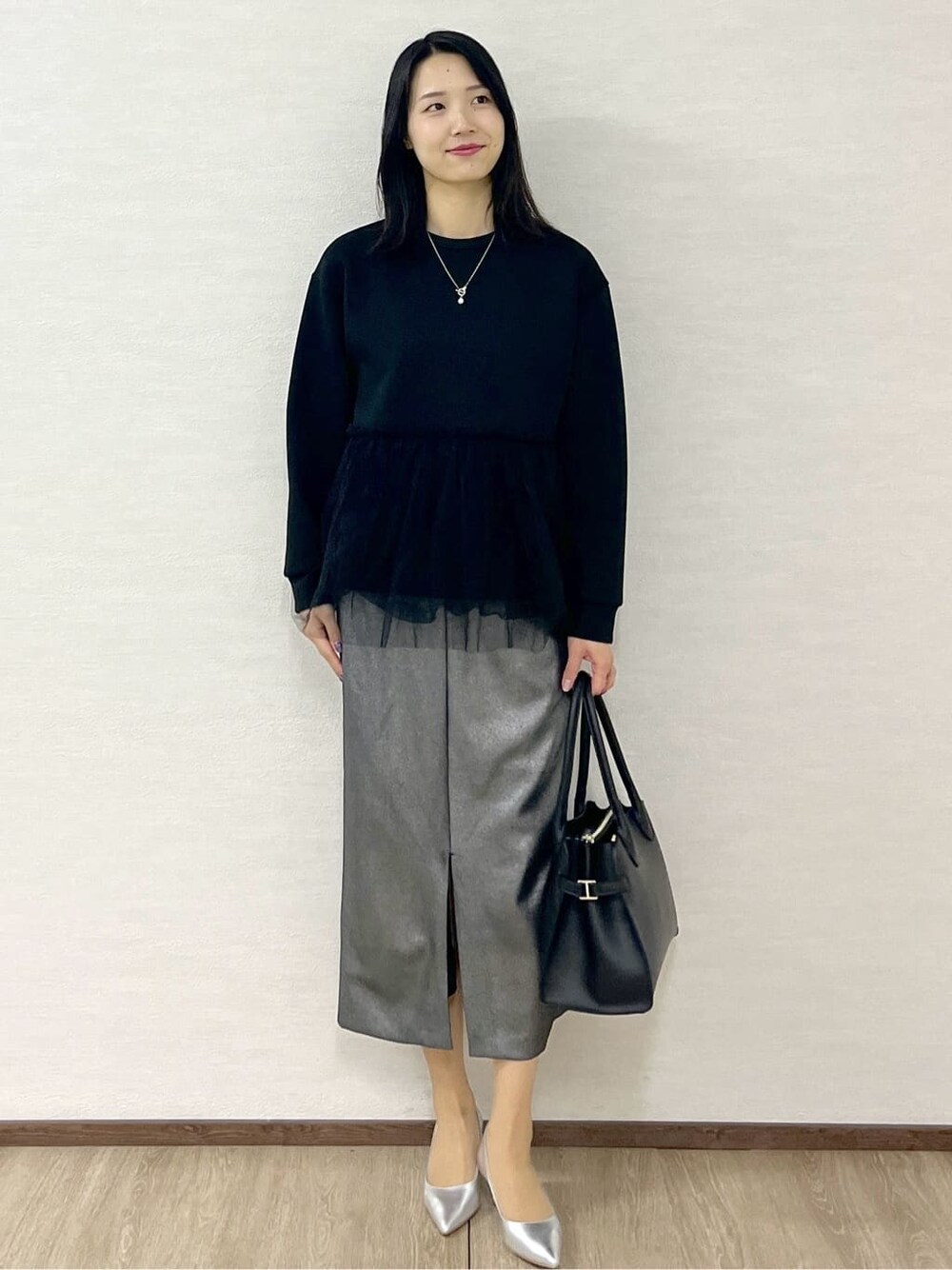 グレー系のノーカラーコート、ブラック系のTシャツ/カットソー、ブラック系のスカートを着用したレディースの冬コーディネートの8枚目の写真
