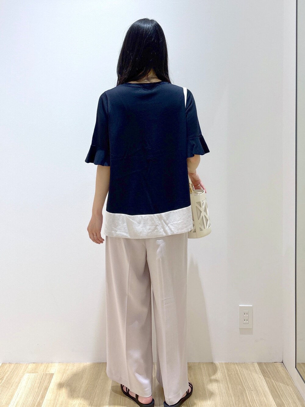 ブラック系のニット/セーター、ベージュ系のその他パンツ、ホワイト系のハンドバッグを着用したレディースの夏コーディネートの4枚目の写真