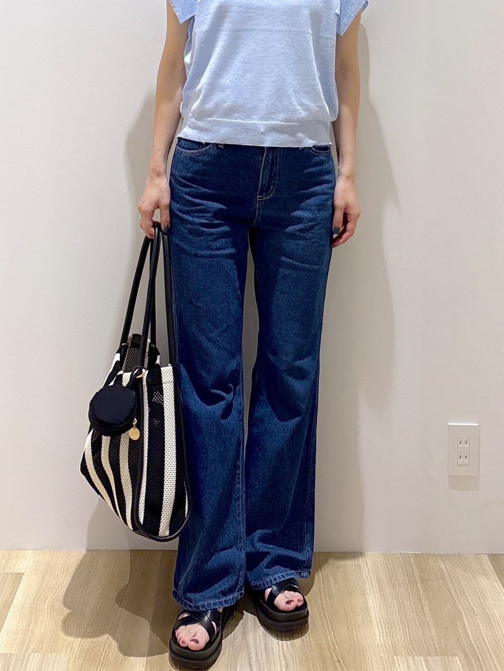 ブルー系のニット/セーター、ブルー系のデニムパンツ、ブラック系のトートバッグを着用したレディースの夏コーディネートの7枚目の写真