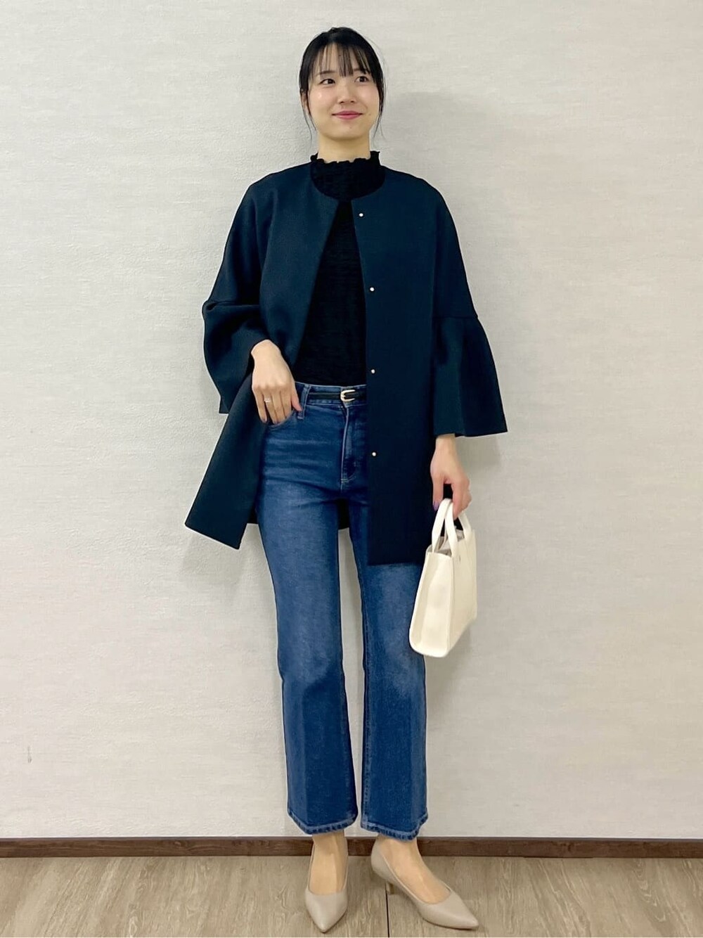 ブルー系のノーカラーコート、ブラック系のTシャツ/カットソー、ブルー系のデニムパンツを着用したレディースの冬コーディネートの6枚目の写真
