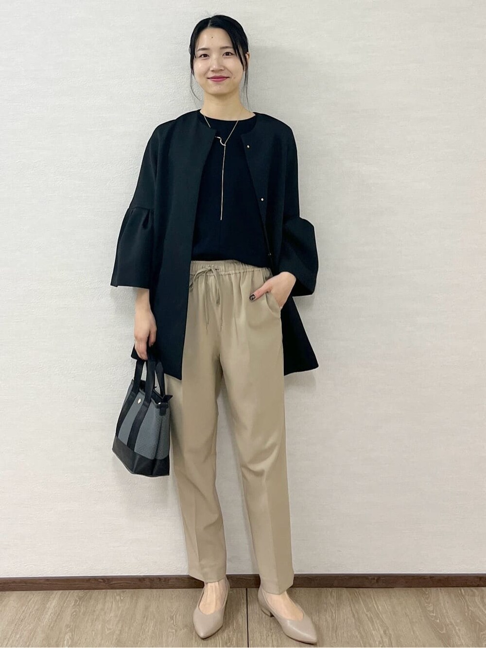 ブラック系のノーカラーコート、ブラック系のTシャツ/カットソー、ベージュ系のその他パンツを着用したレディースの冬コーディネートの2枚目の写真