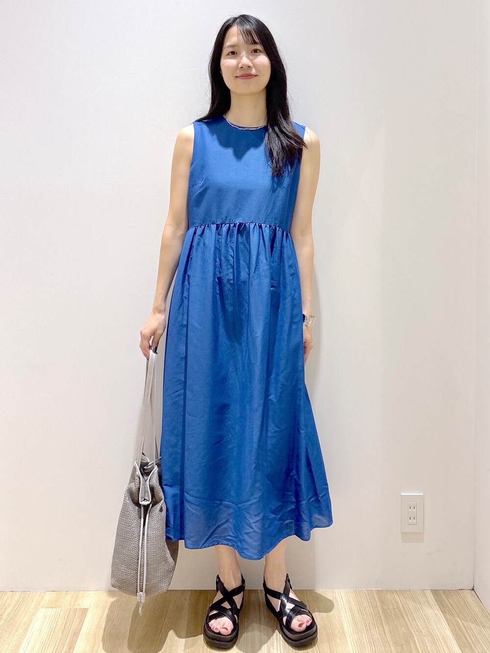 ブルー系のワンピース、ホワイト系のトートバッグ、ブラック系のサンダルを着用したレディースの夏コーディネートの6枚目の写真