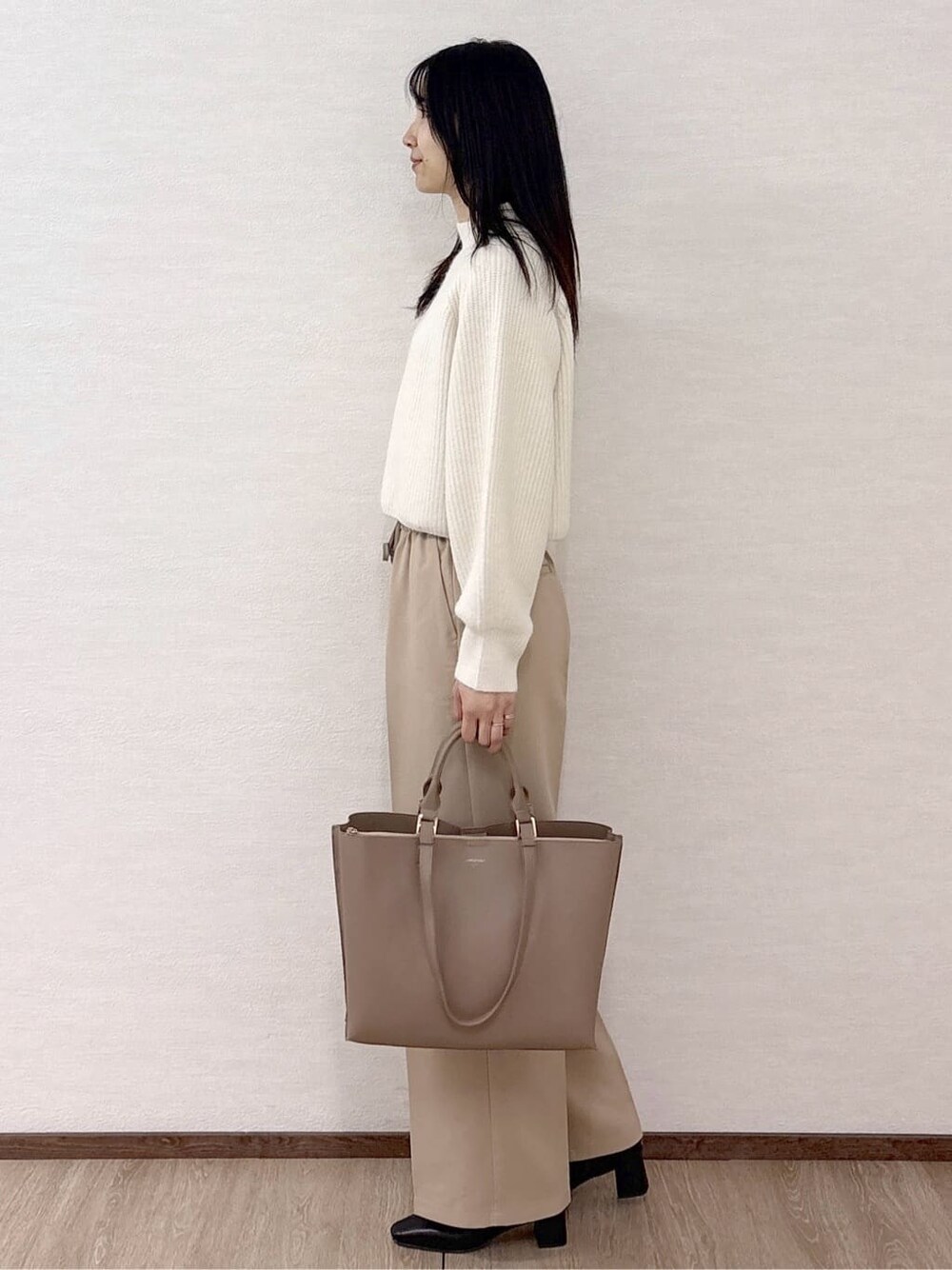 ホワイト系のニット/セーター、ベージュ系のその他パンツ、ベージュ系のトートバッグを着用したレディースの冬コーディネートの3枚目の写真