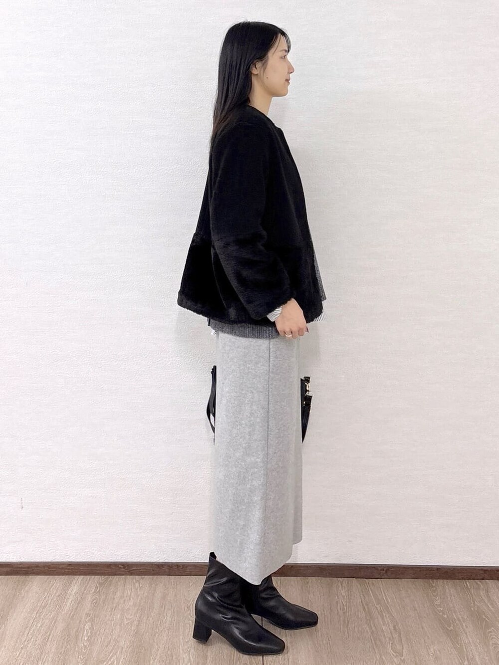 ブラック系のノーカラーコート、グレー系のニット/セーター、ホワイト系のTシャツ/カットソーを着用したレディースの冬コーディネートの5枚目の写真