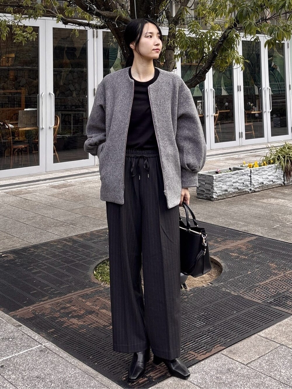 グレー系のノーカラーコート、ブラック系のニット/セーター、グレー系のその他パンツを着用したレディースの冬コーディネートの2枚目の写真