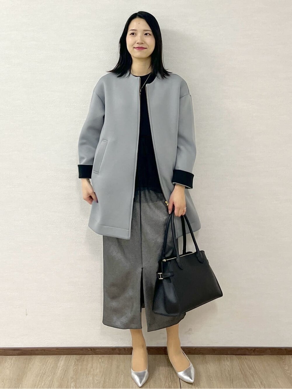 グレー系のノーカラーコート、ブラック系のTシャツ/カットソー、ブラック系のスカートを着用したレディースの冬コーディネートの10枚目の写真