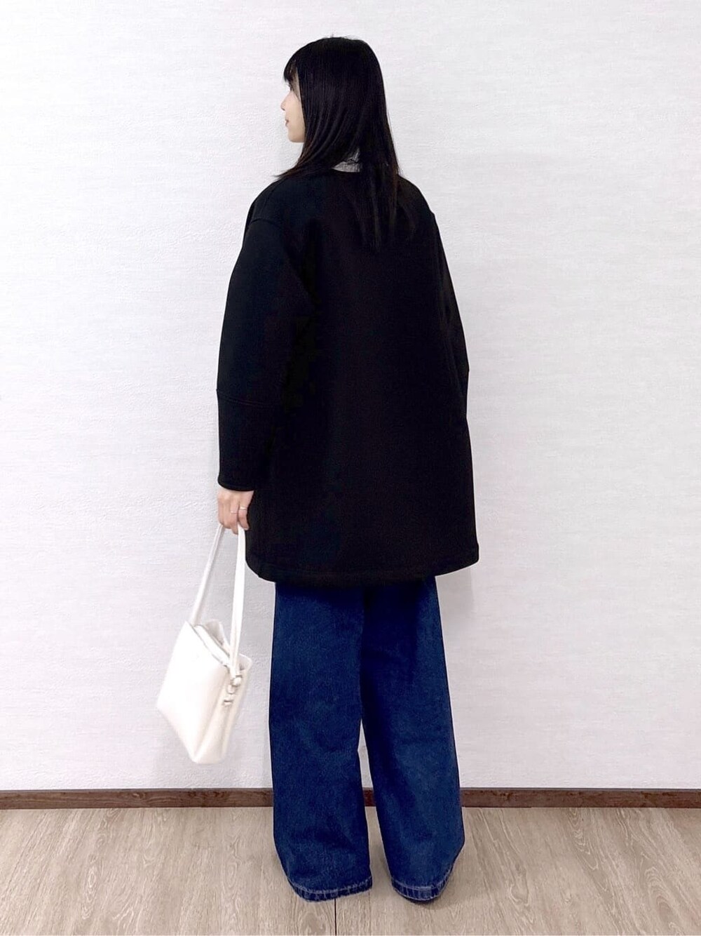 ブラック系のノーカラーコート、ピンク系のシャツ/ブラウス、ブルー系のデニムパンツを着用したレディースの冬コーディネートの4枚目の写真