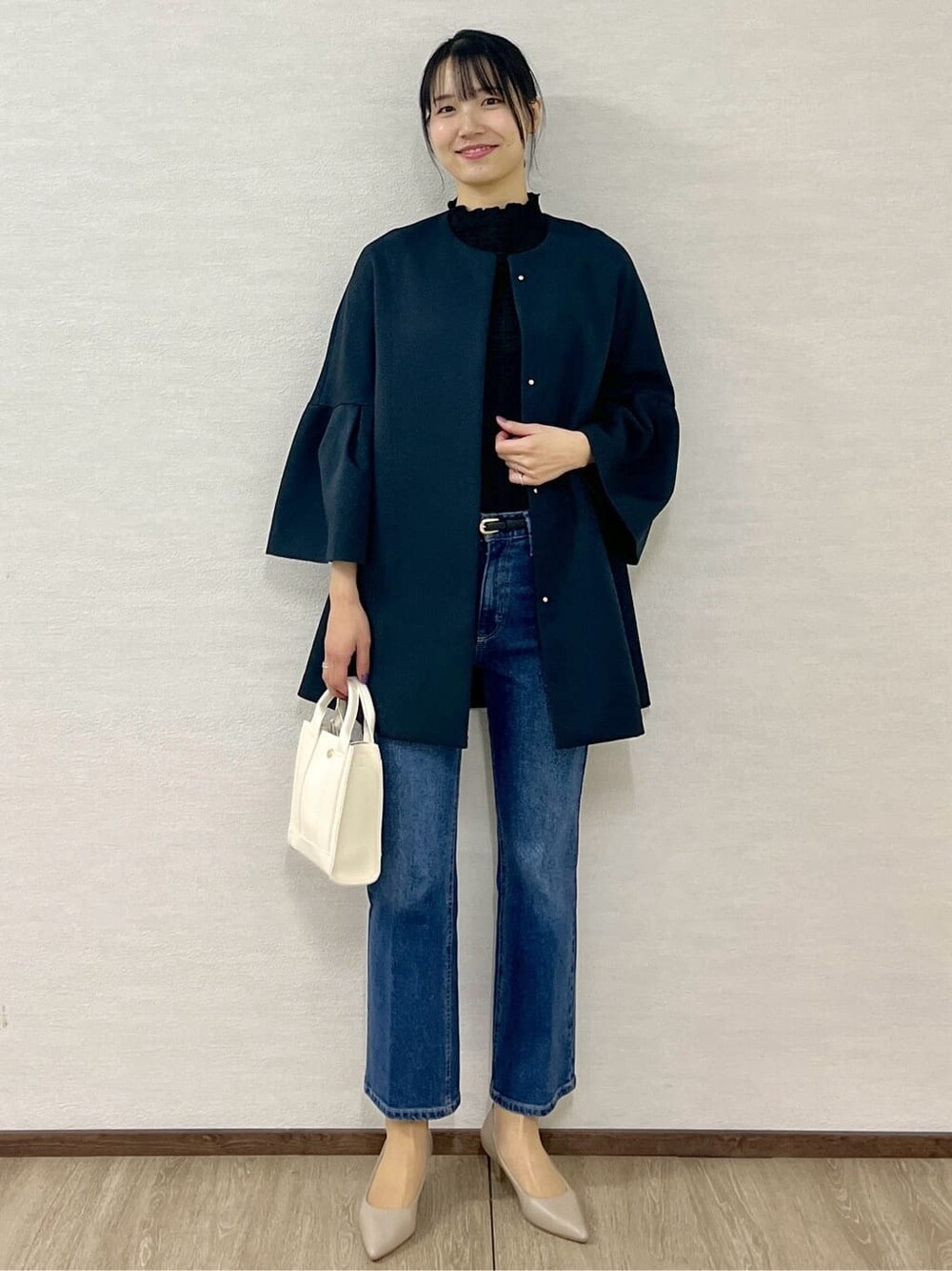 ブルー系のノーカラーコート、ブラック系のTシャツ/カットソー、ブルー系のデニムパンツを着用したレディースの冬コーディネートの2枚目の写真