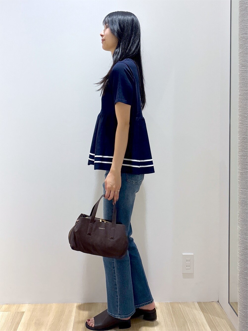 ブルー系のニット/セーター、ブルー系のデニムパンツ、ブラウン系のボストンバッグを着用したレディースの夏コーディネートの3枚目の写真