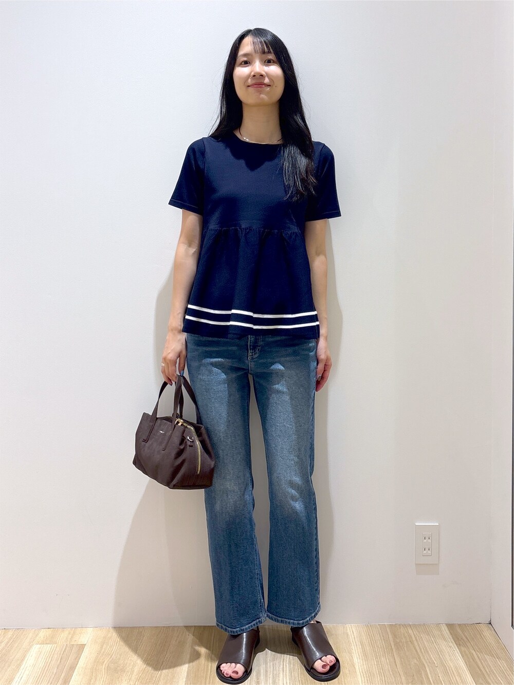 ブルー系のニット/セーター、ブルー系のデニムパンツ、ブラウン系のボストンバッグを着用したレディースの夏コーディネートの8枚目の写真