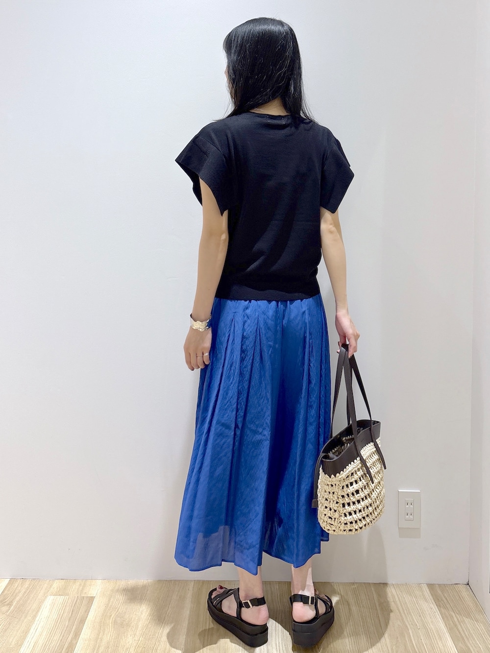ブラック系のニット/セーター、ブルー系のその他パンツ、ブラウン系のトートバッグを着用したレディースの夏コーディネートの4枚目の写真