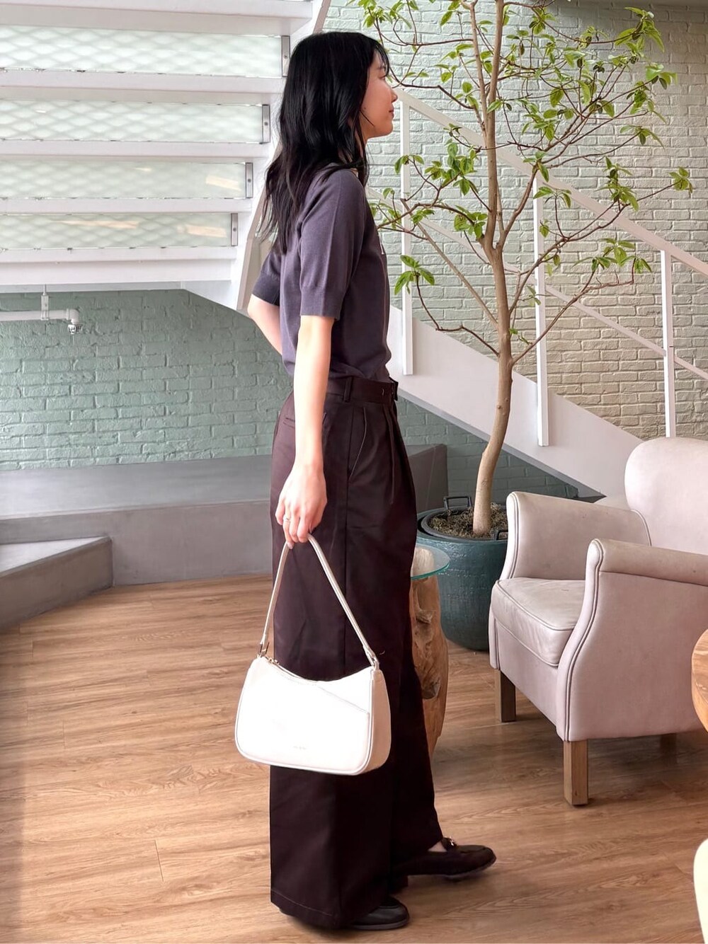グレー系のニット/セーター、ブラウン系のその他パンツ、ホワイト系のショルダーバッグを着用したレディースの春コーディネートの4枚目の写真