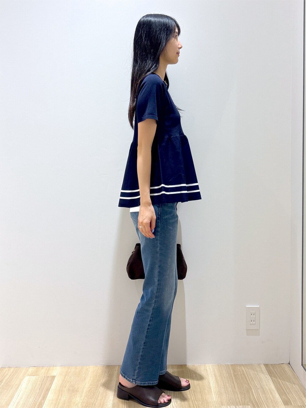 ブルー系のニット/セーター、ブルー系のデニムパンツ、ブラウン系のボストンバッグを着用したレディースの夏コーディネートの5枚目の写真