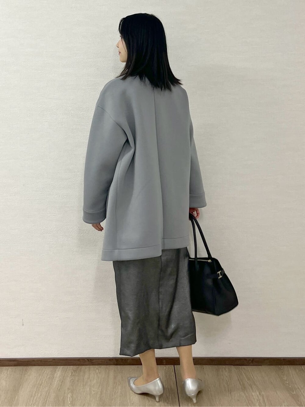 グレー系のノーカラーコート、ブラック系のTシャツ/カットソー、ブラック系のスカートを着用したレディースの冬コーディネートの5枚目の写真