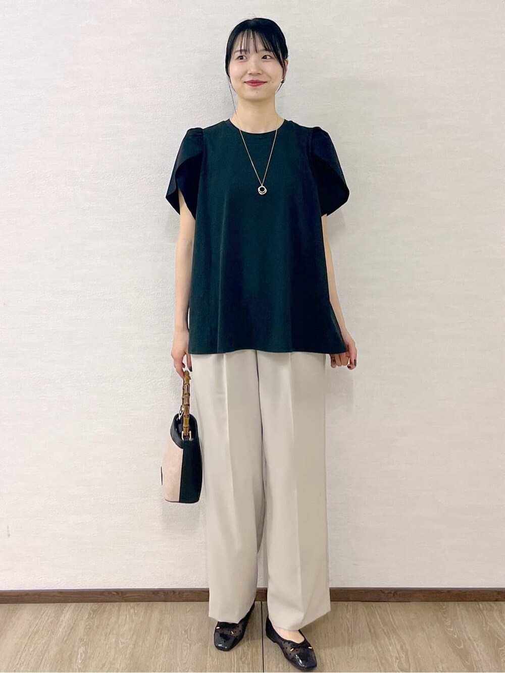ブラック系のTシャツ/カットソー、ベージュ系のその他パンツ、ブラック系のショルダーバッグを着用したレディースの春コーディネートの2枚目の写真