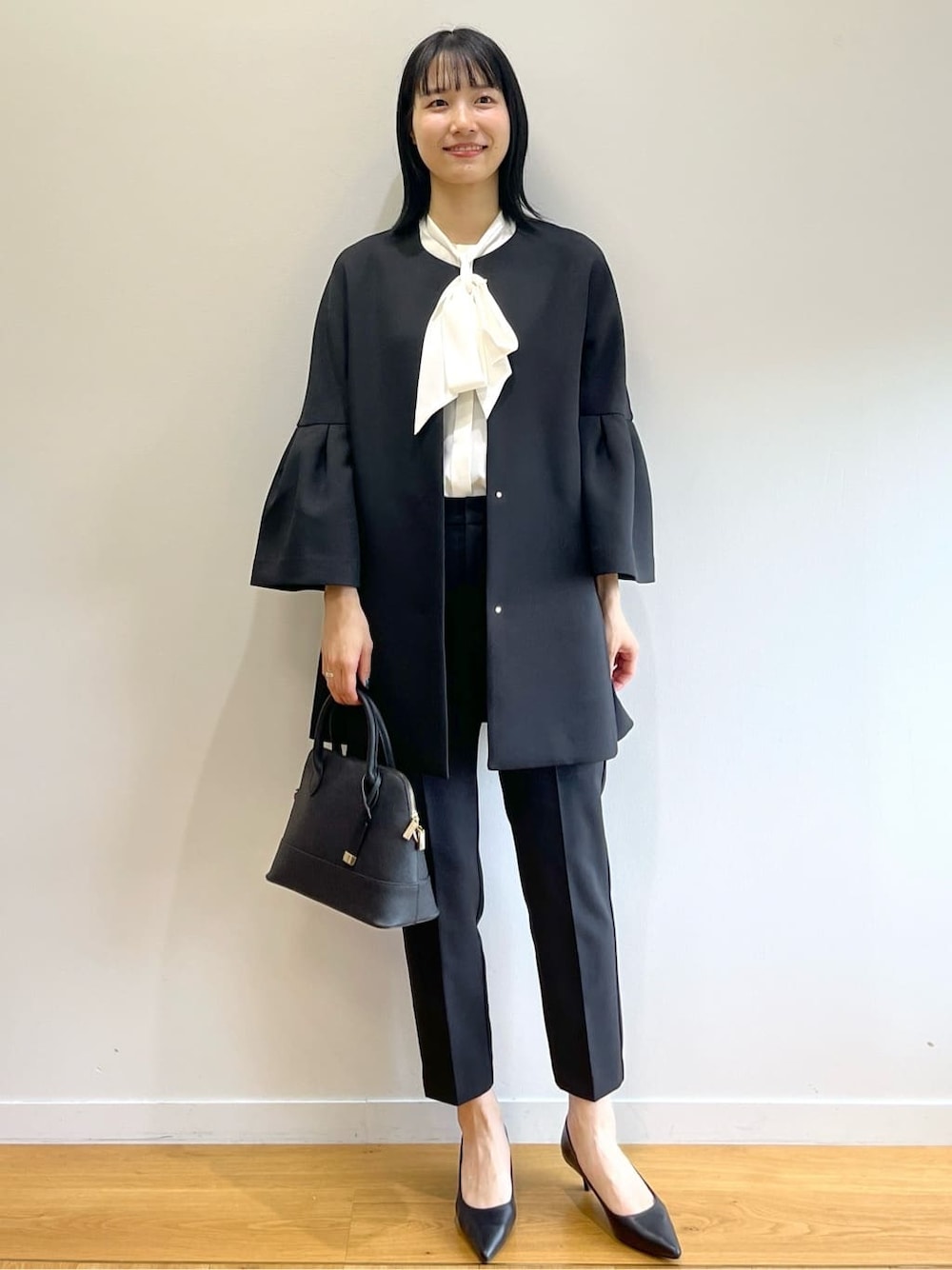 ブラック系のノーカラーコート、ホワイト系のシャツ/ブラウス、ブラック系のその他パンツを着用したレディースの秋コーディネートの9枚目の写真