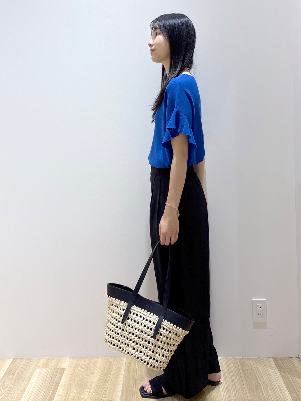 ブルー系のニット/セーター、ブラック系のその他パンツ、ブラック系のトートバッグを着用したレディースの夏コーディネートの3枚目の写真