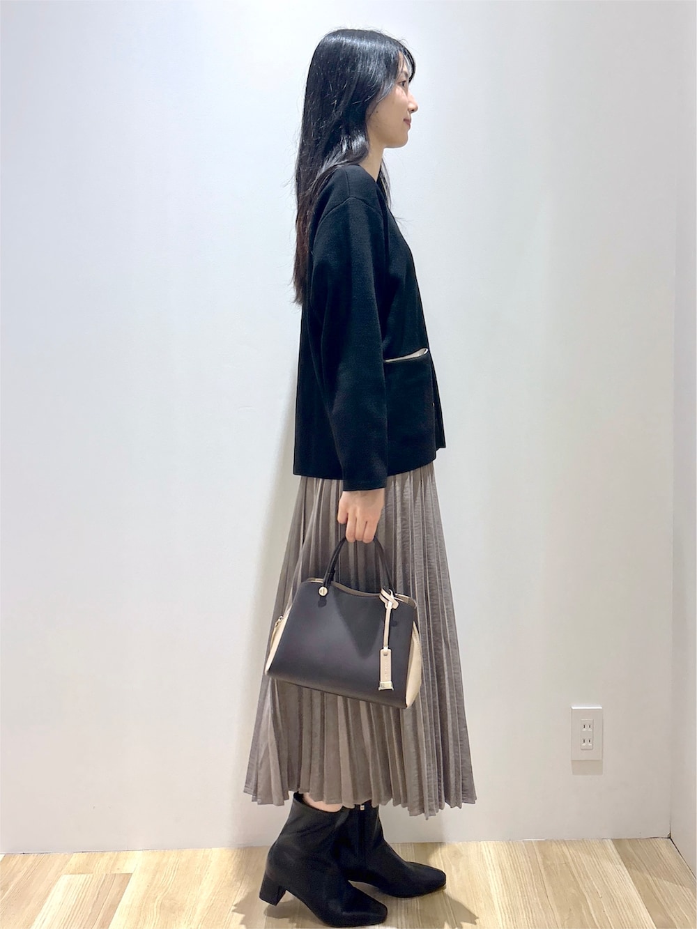ブラック系のカーディガン/ボレロ、ブラウン系のスカート、ブラウン系のボストンバッグを着用したレディースの秋コーディネートの5枚目の写真