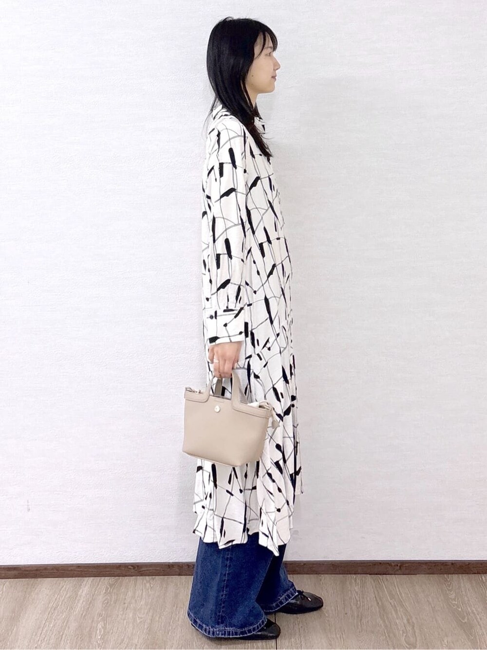ベージュ系のワンピース、ブルー系のデニムパンツ、ベージュ系のショルダーバッグを着用したレディースの春コーディネートの5枚目の写真