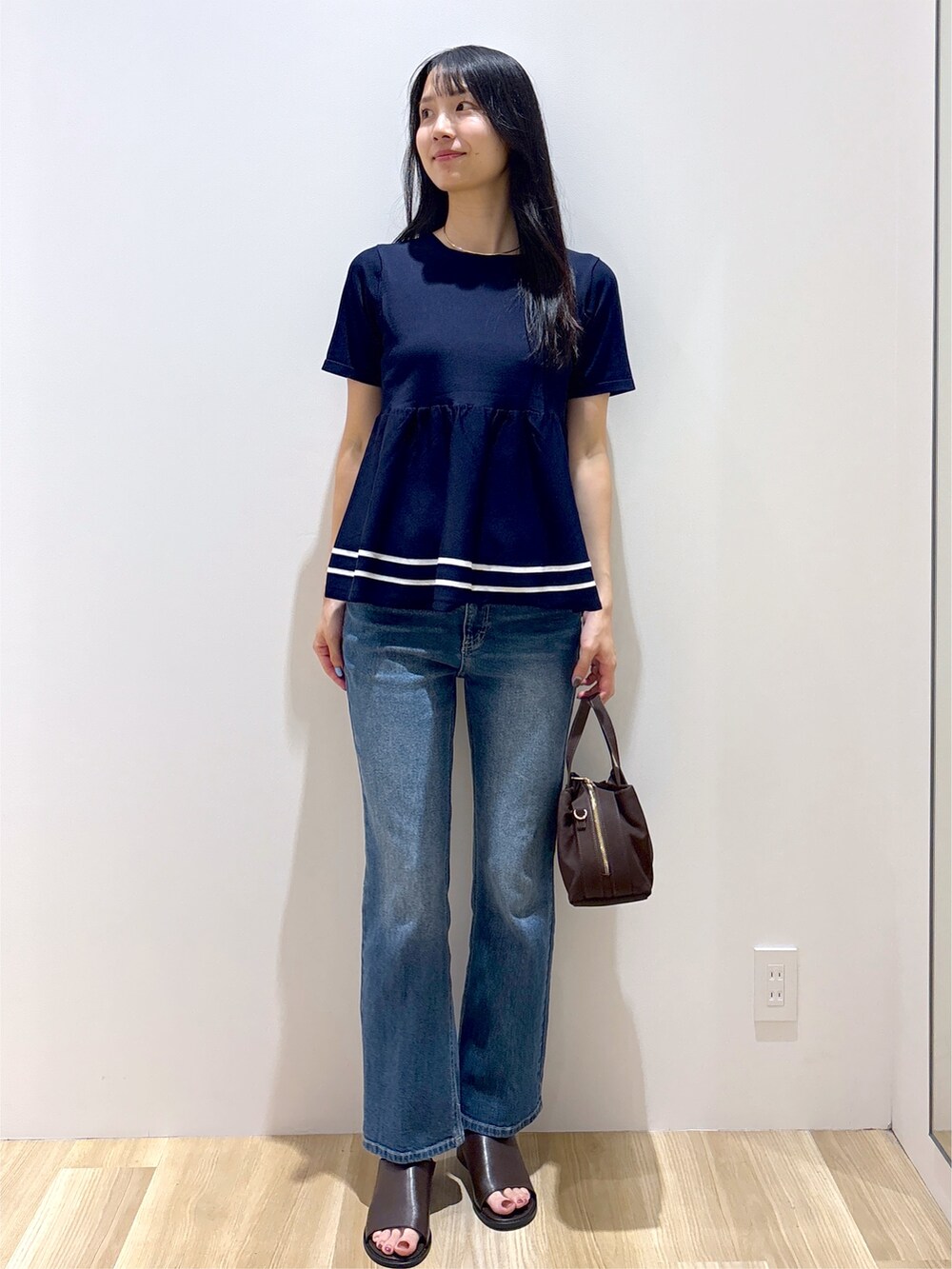 ブルー系のニット/セーター、ブルー系のデニムパンツ、ブラウン系のボストンバッグを着用したレディースの夏コーディネートの9枚目の写真