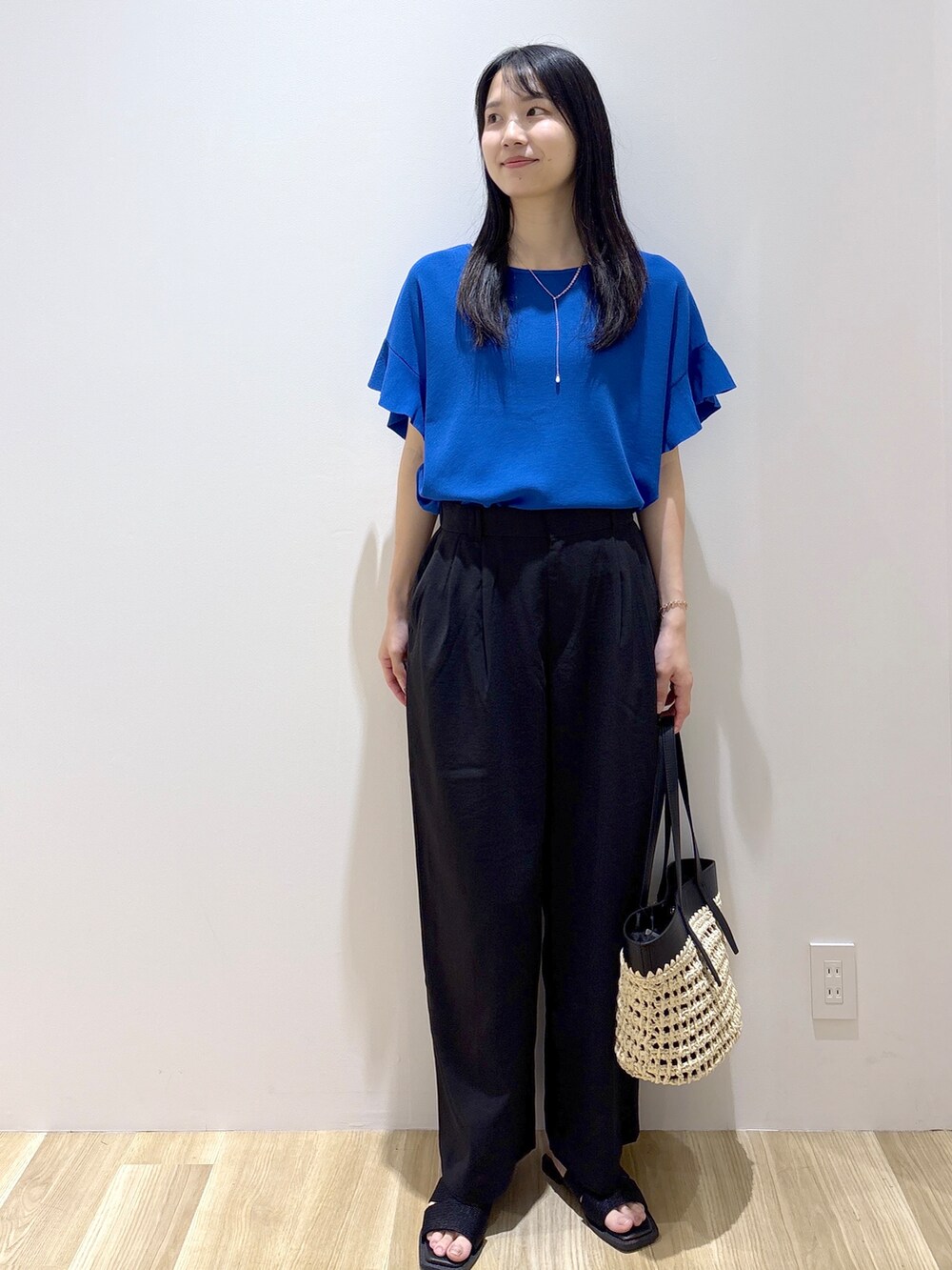 ブルー系のニット/セーター、ブラック系のその他パンツ、ブラック系のトートバッグを着用したレディースの夏コーディネートの2枚目の写真