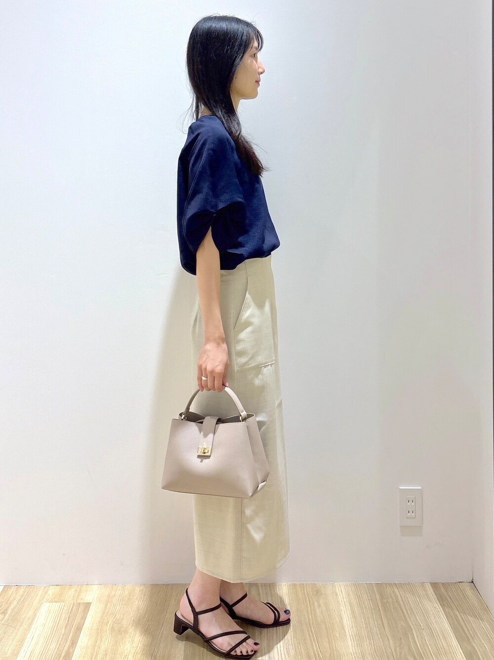 ブルー系のシャツ/ブラウス、ベージュ系のスカート、ベージュ系のハンドバッグを着用したレディースの夏コーディネートの5枚目の写真