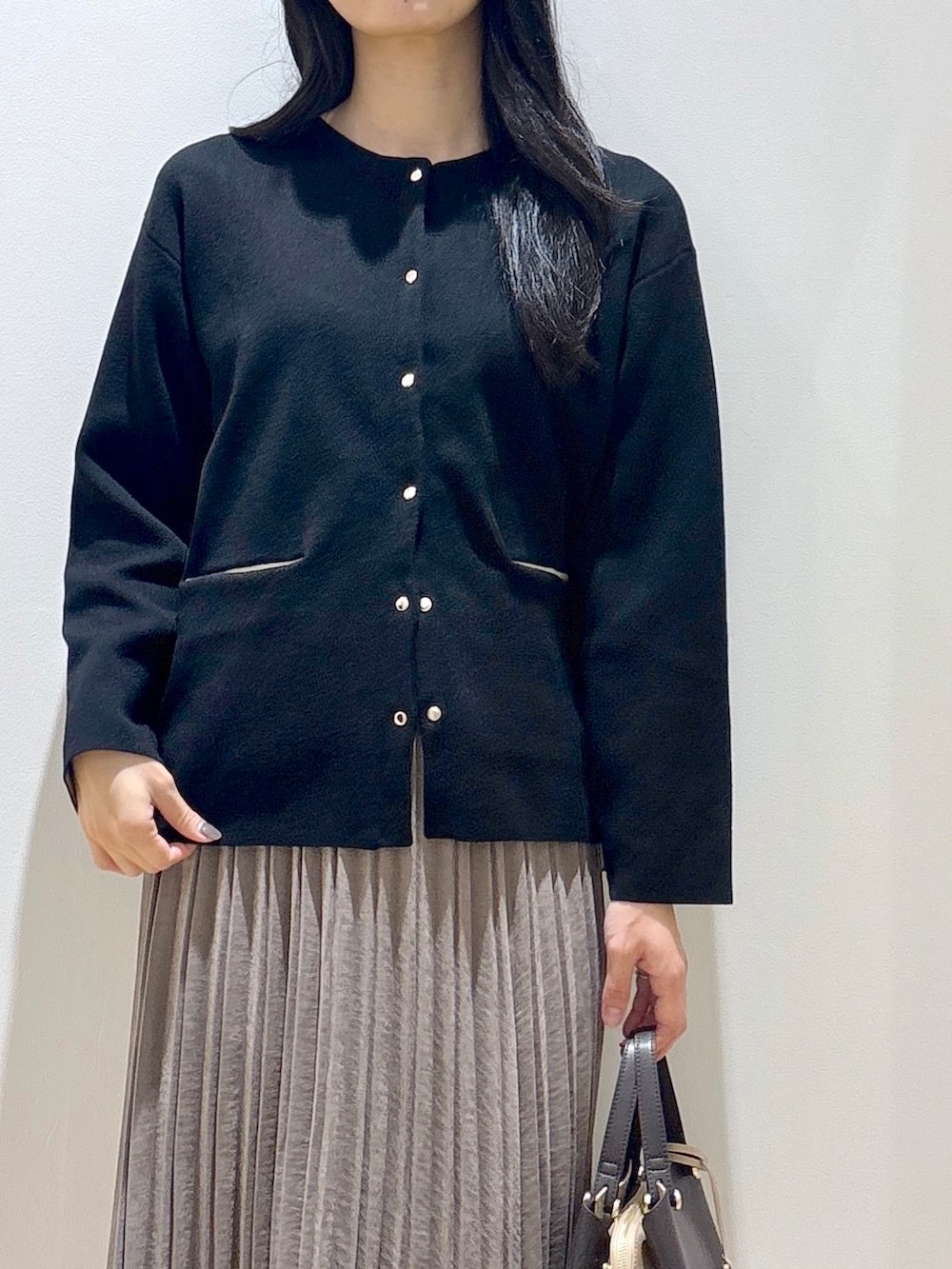 ブラック系のカーディガン/ボレロ、ブラウン系のスカート、ブラウン系のボストンバッグを着用したレディースの秋コーディネートの6枚目の写真