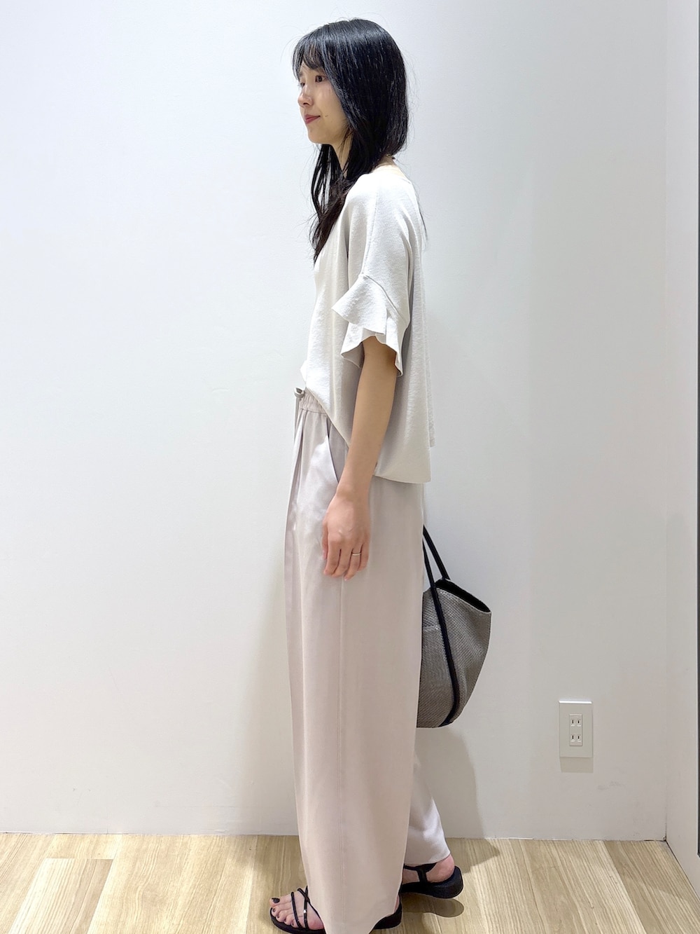ベージュ系のその他パンツ、ブラック系のサンダル、グレー系のトートバッグを着用したレディースの春コーディネートの3枚目の写真