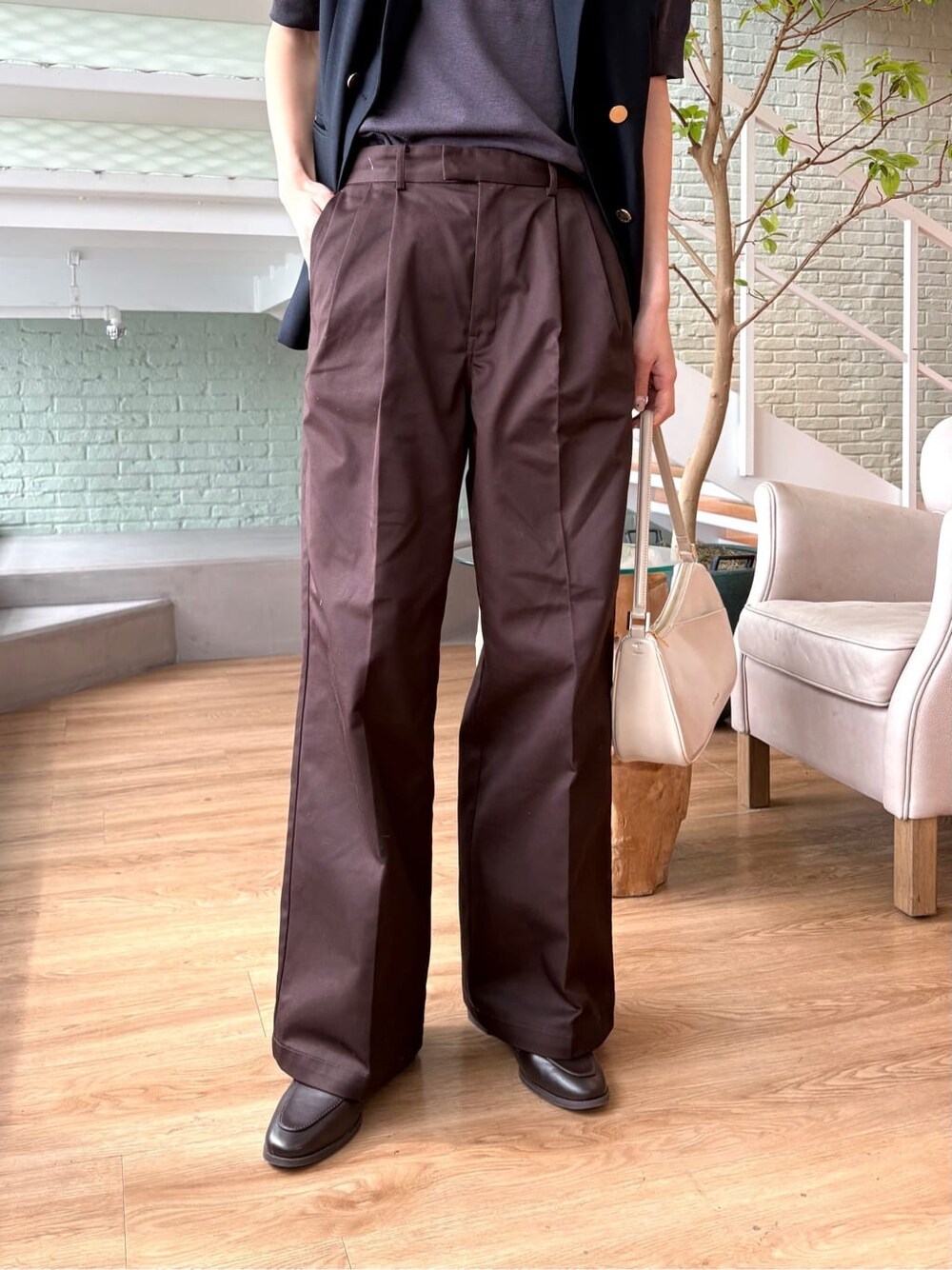 グレー系のニット/セーター、ブラウン系のその他パンツ、ホワイト系のショルダーバッグを着用したレディースの春コーディネートの6枚目の写真