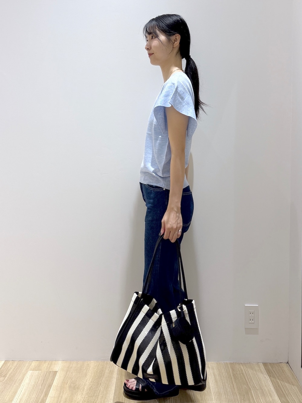 ブルー系のニット/セーター、ブルー系のデニムパンツ、ブラック系のトートバッグを着用したレディースの夏コーディネートの3枚目の写真
