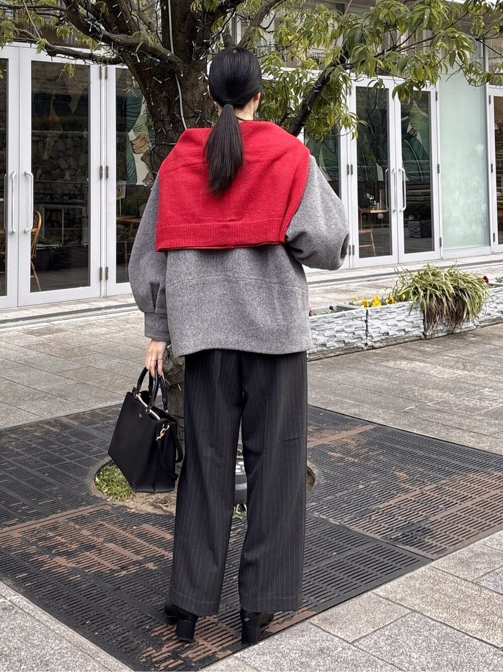 グレー系のノーカラーコート、ブラック系のニット/セーター、グレー系のその他パンツを着用したレディースの冬コーディネートの6枚目の写真
