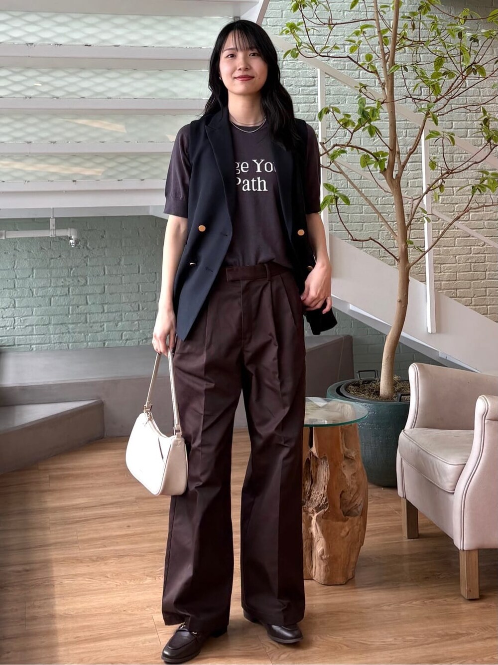 グレー系のニット/セーター、ブラウン系のその他パンツ、ホワイト系のショルダーバッグを着用したレディースの春コーディネートの9枚目の写真