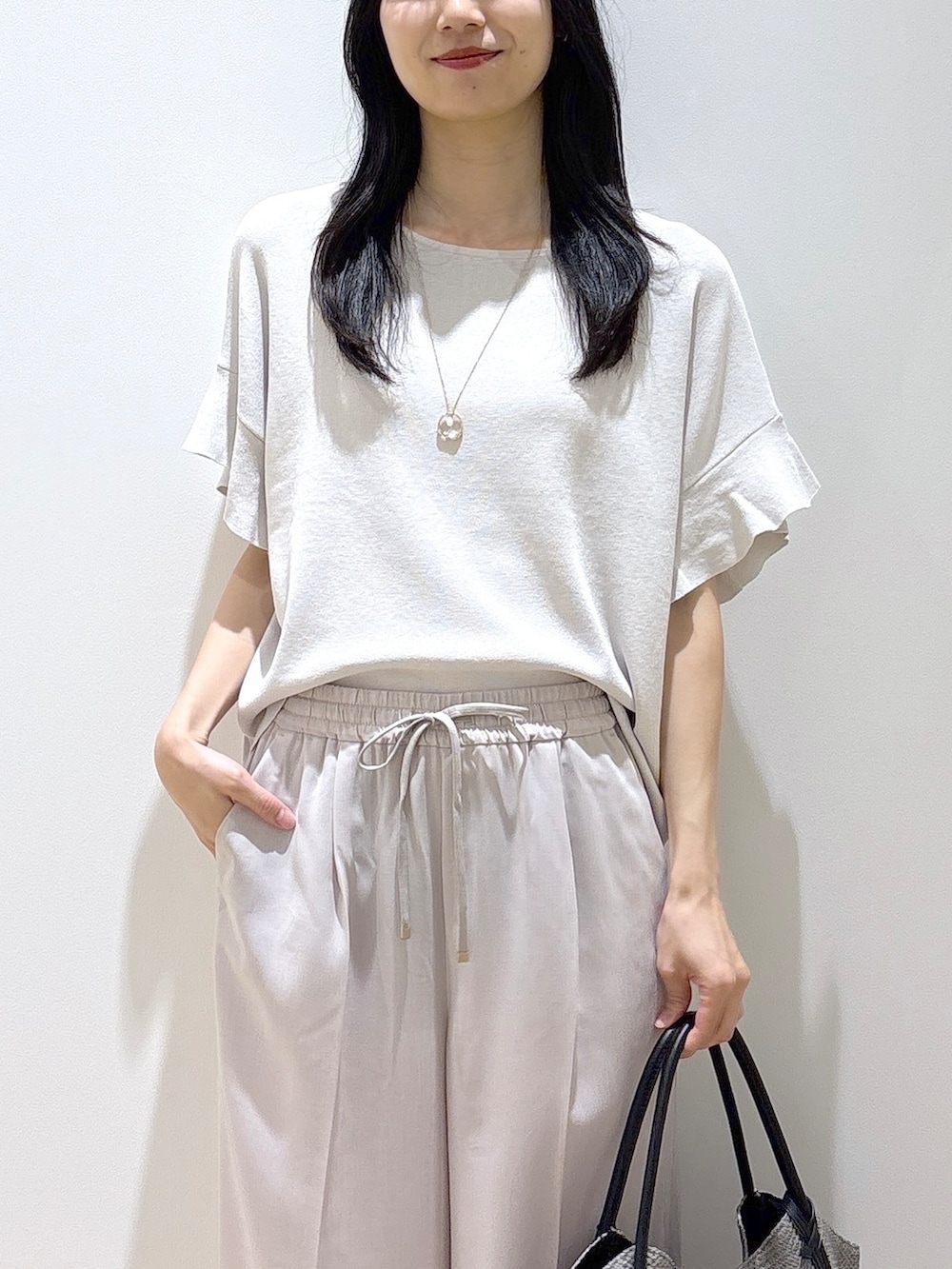 ベージュ系のその他パンツ、ブラック系のサンダル、グレー系のトートバッグを着用したレディースの春コーディネートの6枚目の写真