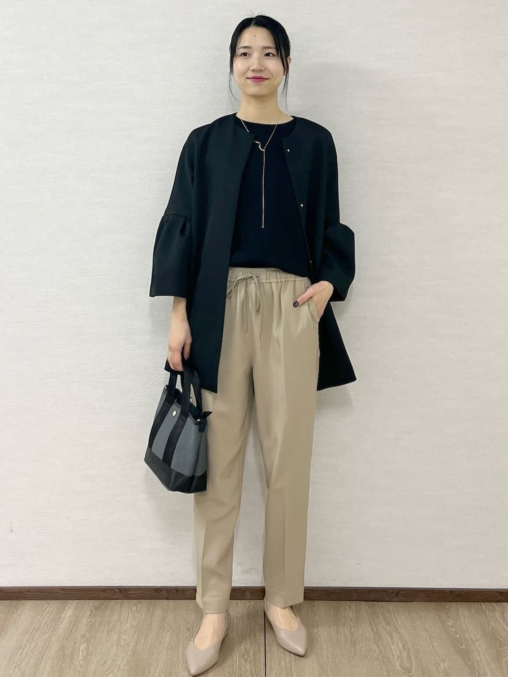 ブラック系のノーカラーコート、ブラック系のTシャツ/カットソー、ベージュ系のその他パンツを着用したレディースの冬コーディネートの3枚目の写真