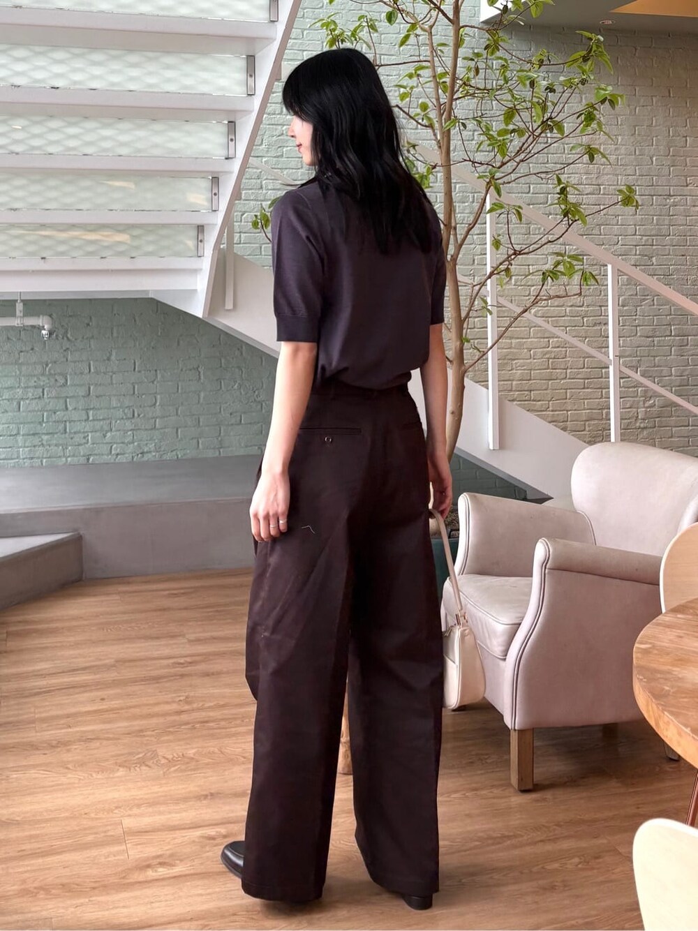 グレー系のニット/セーター、ブラウン系のその他パンツ、ホワイト系のショルダーバッグを着用したレディースの春コーディネートの5枚目の写真