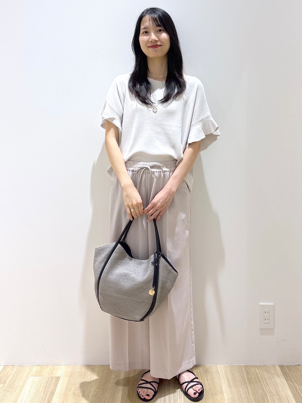 ベージュ系のその他パンツ、ブラック系のサンダル、グレー系のトートバッグを着用したレディースの春コーディネートの10枚目の写真