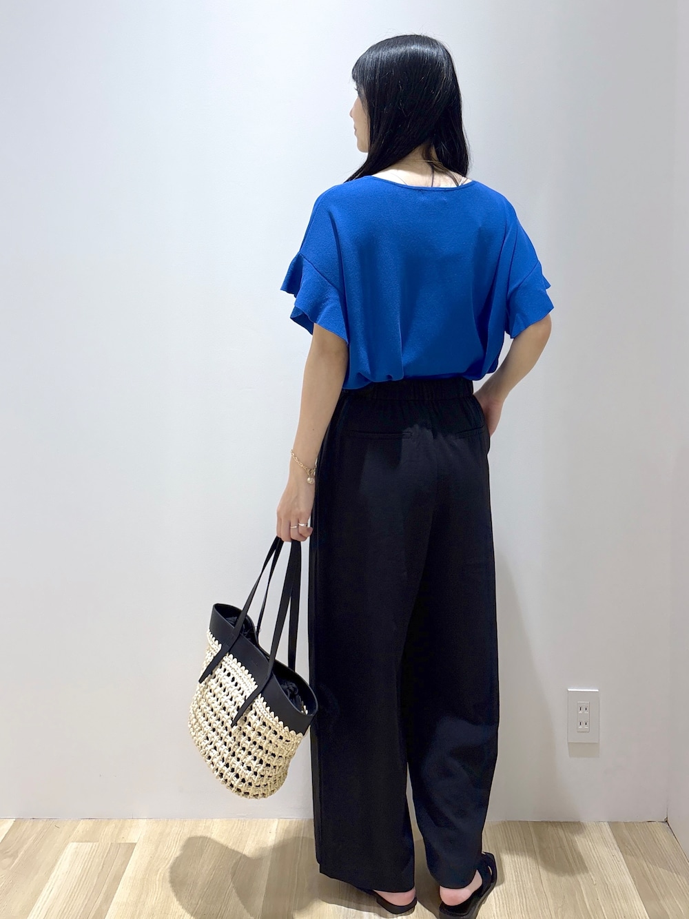 ブルー系のニット/セーター、ブラック系のその他パンツ、ブラック系のトートバッグを着用したレディースの夏コーディネートの4枚目の写真