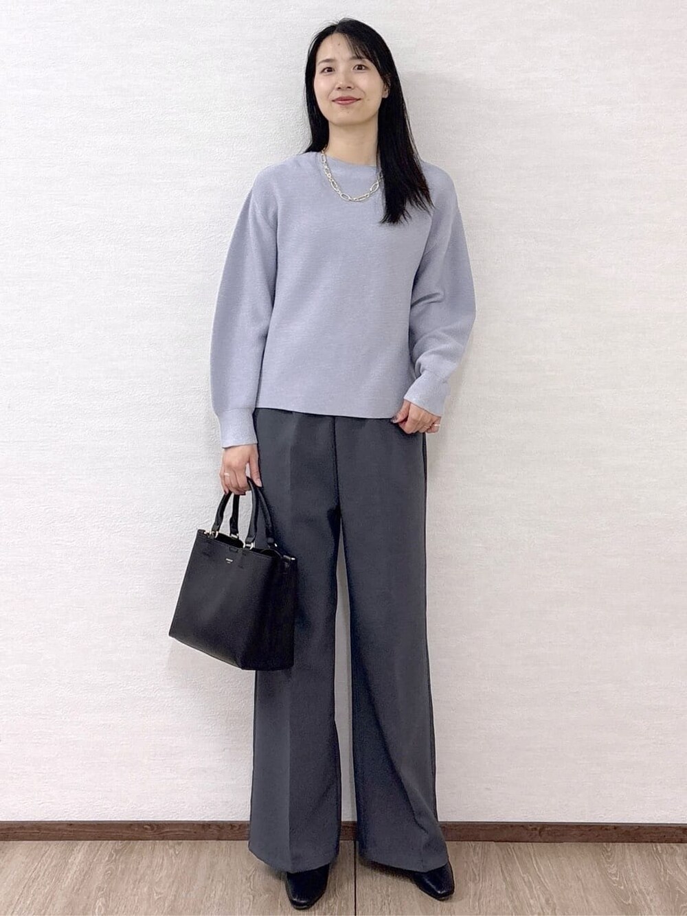 ブルー系のニット/セーター、グレー系のその他パンツ、ブラック系のトートバッグを着用したレディースの冬コーディネートの2枚目の写真